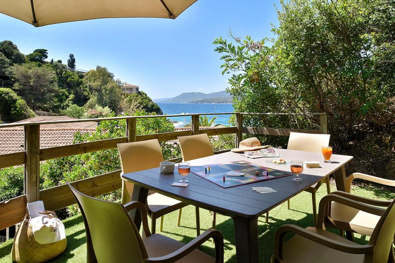 Une table avec des verres et des journaux sur une terrasse ensoleillée avec vue sur la mer.