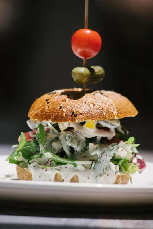 Un mini-burger garni est présenté sur une assiette blanche.
