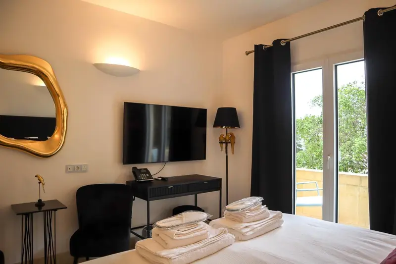 Une chambre d'hôtel lumineuse avec un lit fait et un bureau.