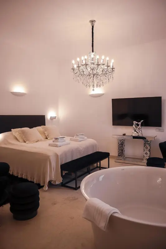 Une chambre lumineuse avec un grand lit et une baignoire.