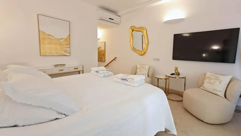 Une chambre lumineuse avec un grand lit et un coin salon.