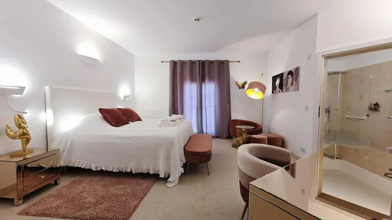 Chambre lumineuse avec un grand lit et un espace détente.