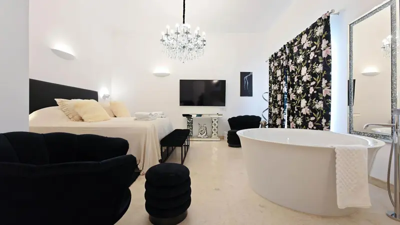 Une chambre lumineuse avec un grand lit et une baignoire îlot.