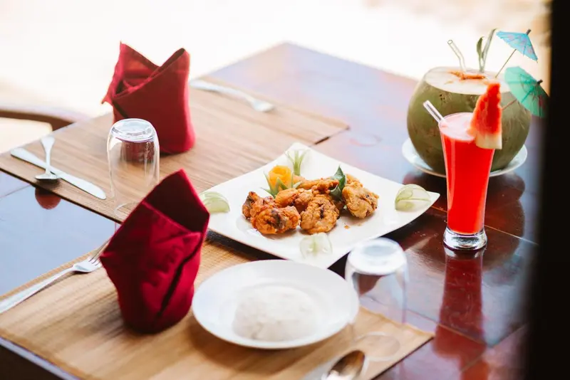 Une table est dressée avec des plats colorés et des boissons tropicales.