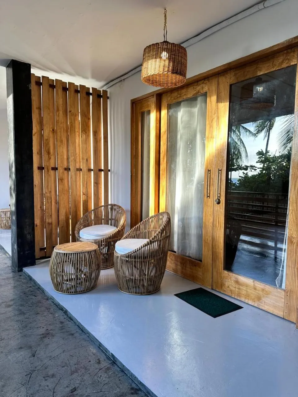 Deux fauteuils en rotin invitent à la détente sur une terrasse ombragée.