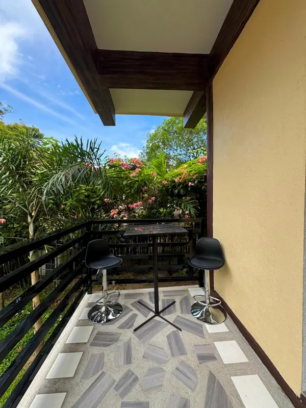 Terrasse avec deux tabourets de bar et vue sur la végétation.