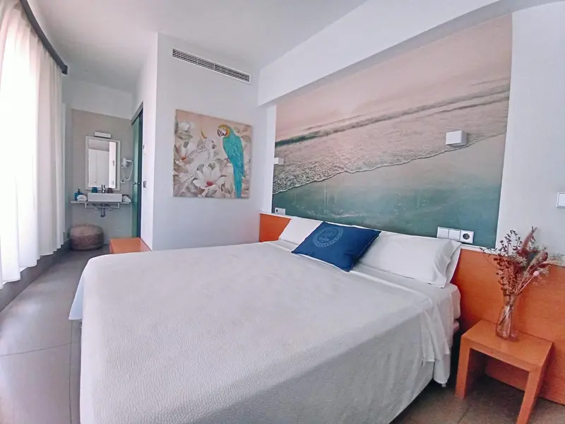 Une chambre lumineuse avec un grand lit et une décoration murale évoquant la mer.