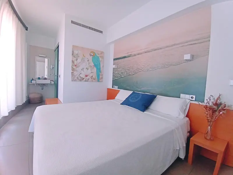 Une chambre lumineuse avec un grand lit recouvert de blanc.
