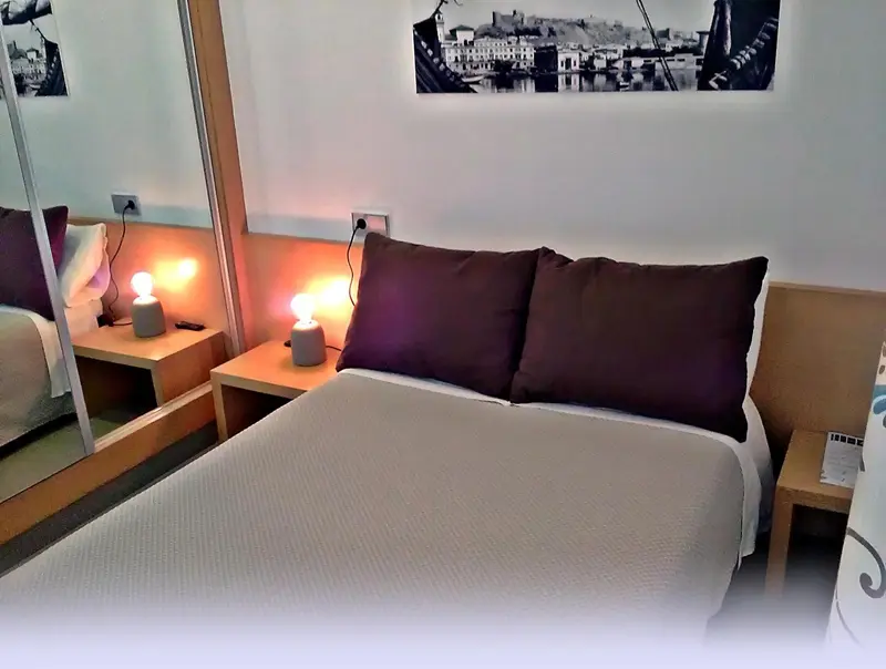 Une chambre lumineuse avec un grand lit et des tables de chevet.