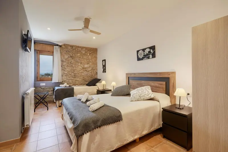 Une chambre lumineuse avec deux lits et un mur en pierre.
