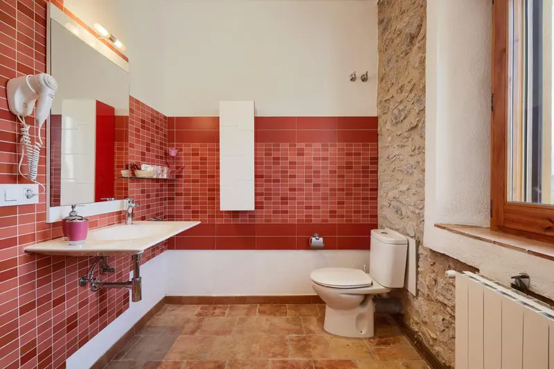 Une salle de bain carrelée avec lavabo, toilette et radiateur.