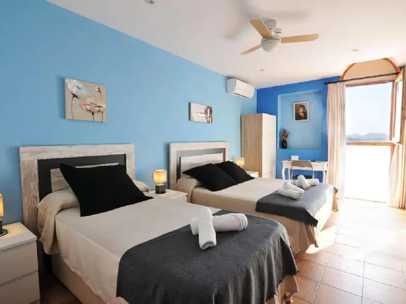 Chambre lumineuse avec deux lits et une décoration sobre.
