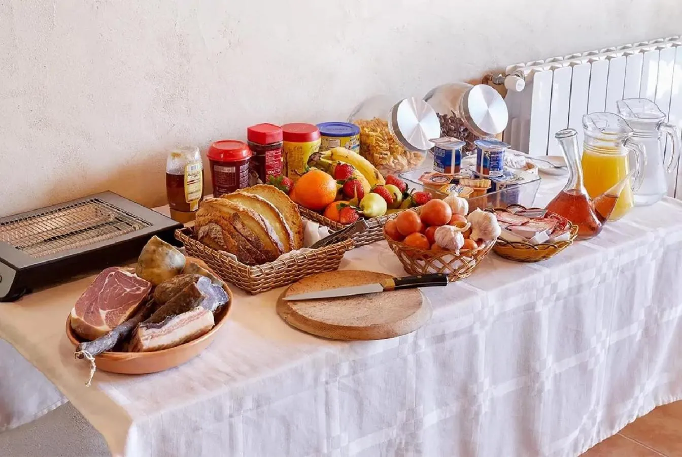 Table garnie de viennoiseries, fruits, confitures et charcuteries.