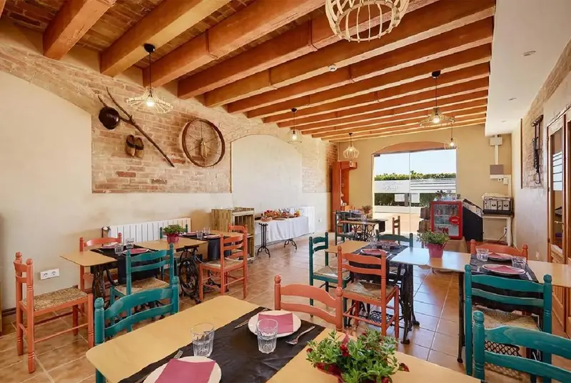 Une salle de restaurant lumineuse avec des tables colorées et un décor rustique.