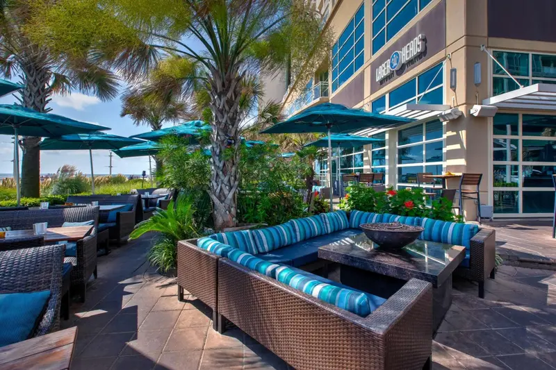 Terrasse ombragée avec mobilier de jardin et végétation tropicale.