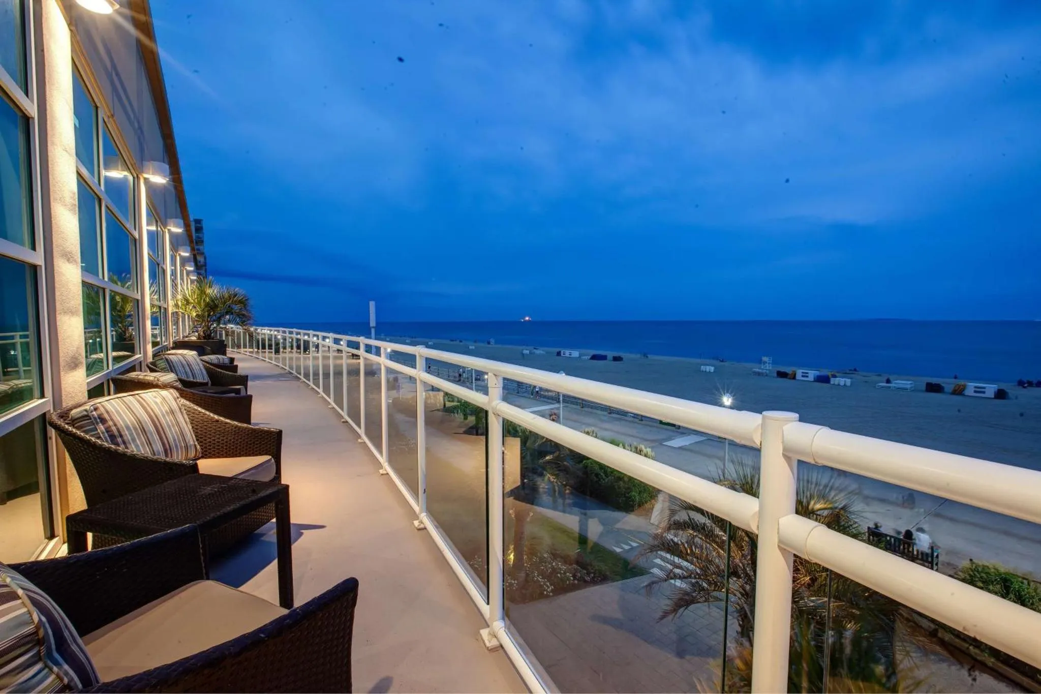 Terrasse avec mobilier d'extérieur donnant sur la mer au crépuscule.