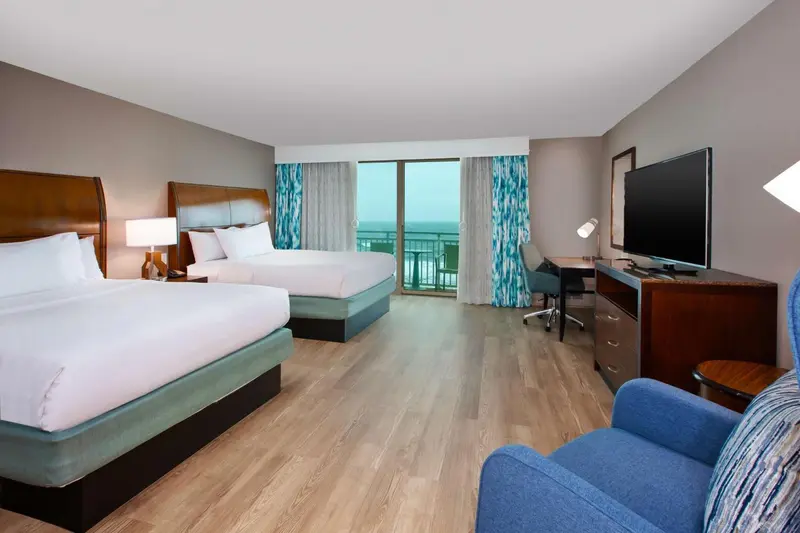 Une chambre d'hôtel lumineuse avec deux lits et une vue sur la mer.