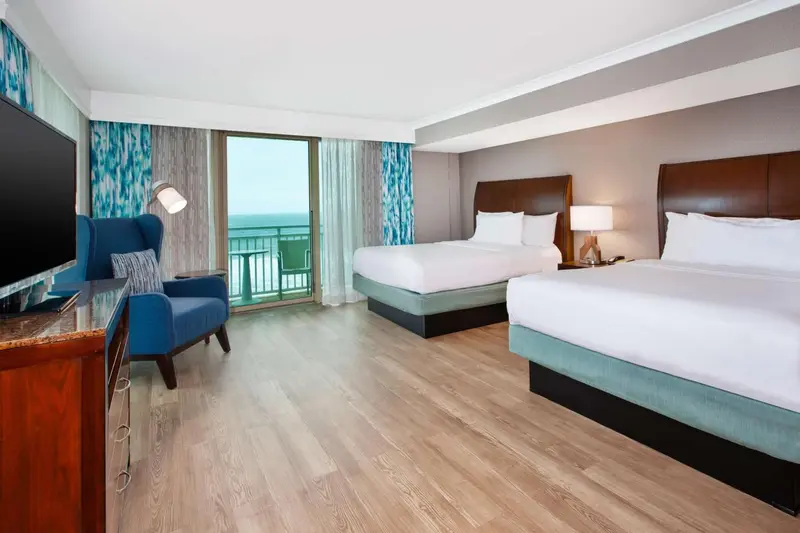 Une chambre d'hôtel lumineuse avec deux lits et une vue sur la mer.