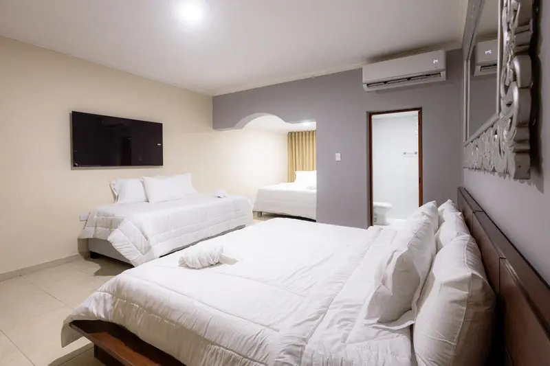 Une chambre d'hôtel avec deux lits doubles et un téléviseur mural.