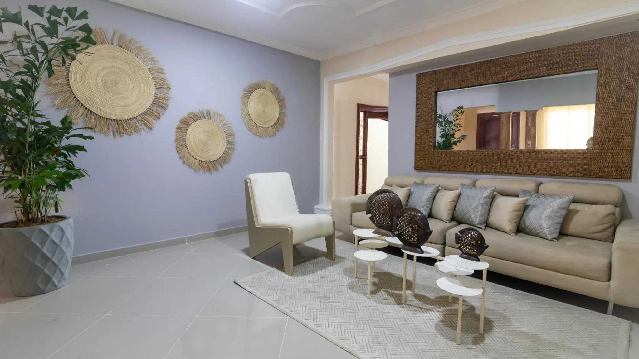 Un salon clair et moderne avec un canapé, des fauteuils et des décorations murales.