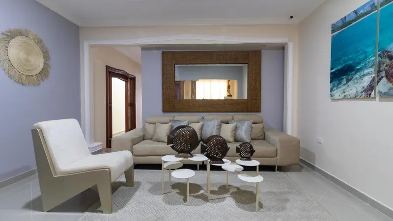 Un salon clair avec un canapé beige et des fauteuils.