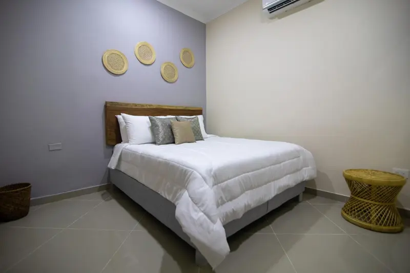 Une chambre lumineuse avec un grand lit recouvert d'une couette blanche et de coussins.