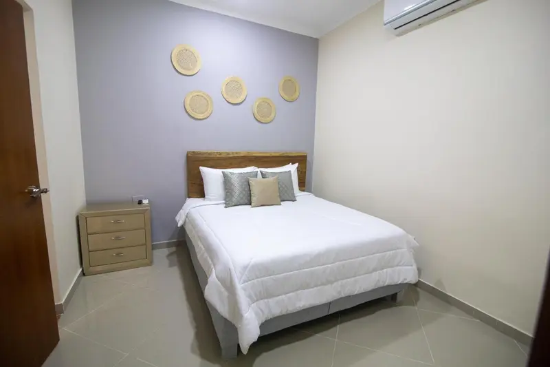 Une chambre lumineuse avec un lit double et des éléments décoratifs au mur.