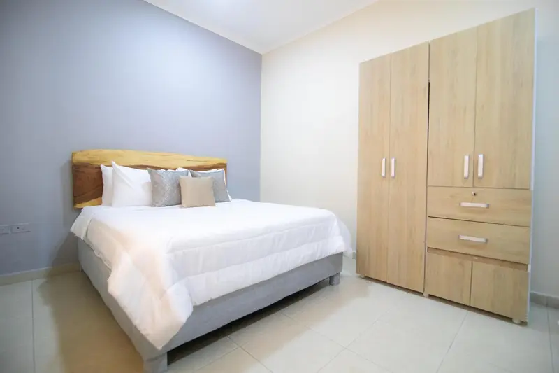 Une chambre lumineuse avec un grand lit et une armoire en bois.