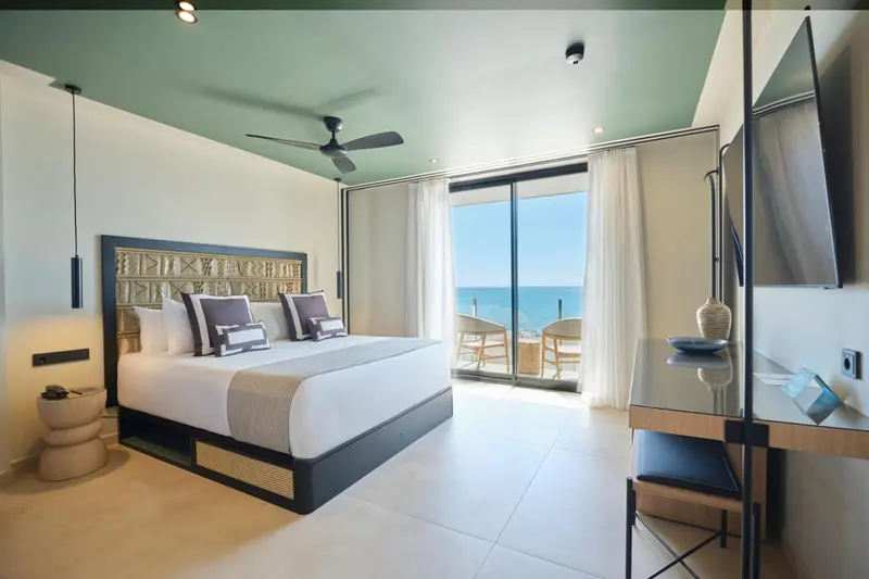 Une chambre lumineuse avec un grand lit et une vue sur la mer.
