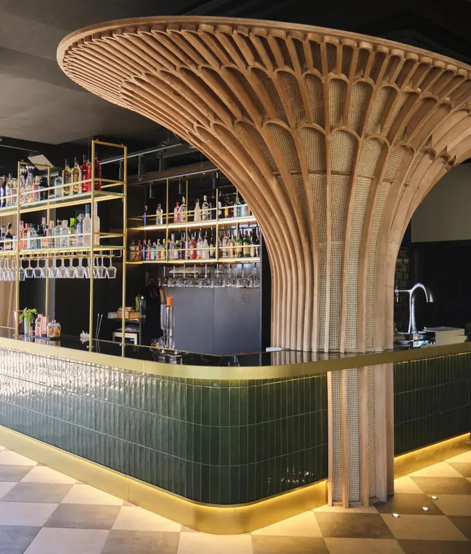 Un comptoir de bar moderne avec une structure en bois sculptée au-dessus.