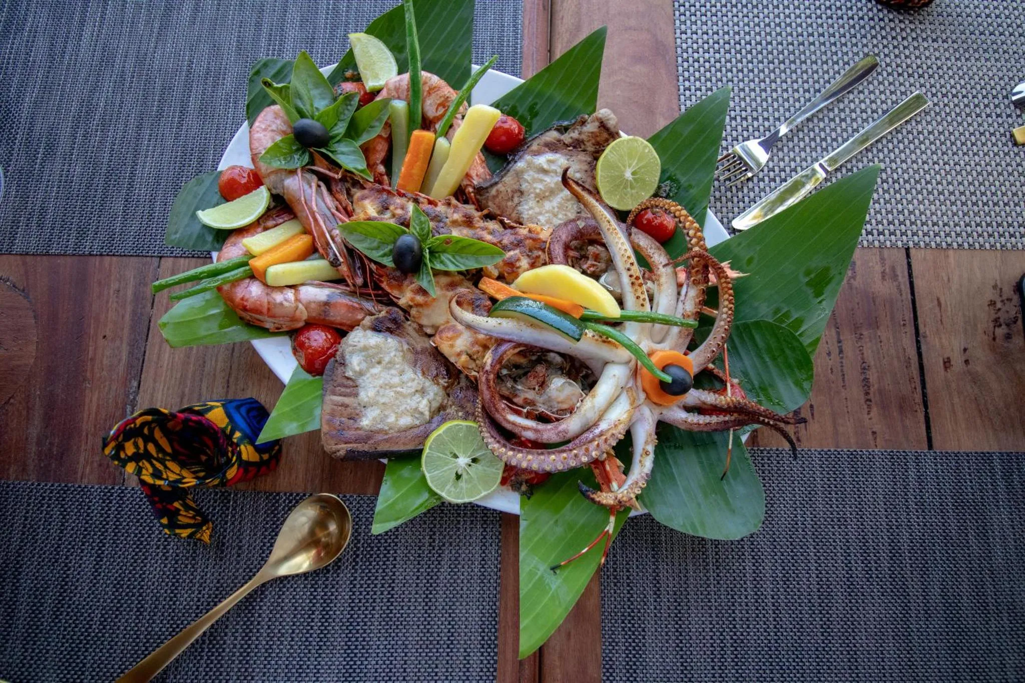 Assiette de fruits de mer frais décorée de feuilles vertes et de citron.
