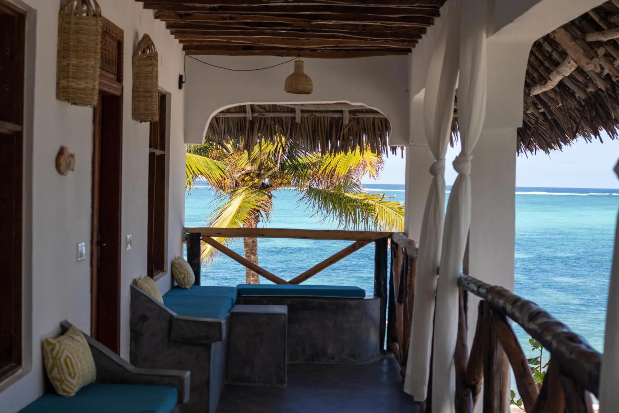 Terrasse ombragée donnant sur la mer et la végétation tropicale.