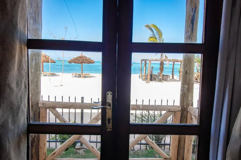 Vue sur une plage de sable blanc avec des parasols et des structures en bois.