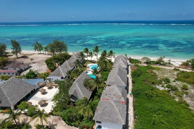 Vue aérienne d'un complexe hôtelier bordant une plage de sable blanc et une mer turquoise.