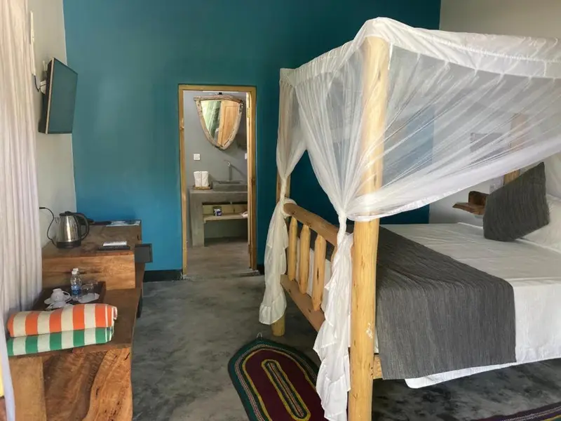 Une chambre lumineuse avec un lit à baldaquin et une commode en bois.