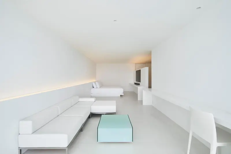 Espace de vie minimaliste avec canapé blanc et table basse turquoise.
