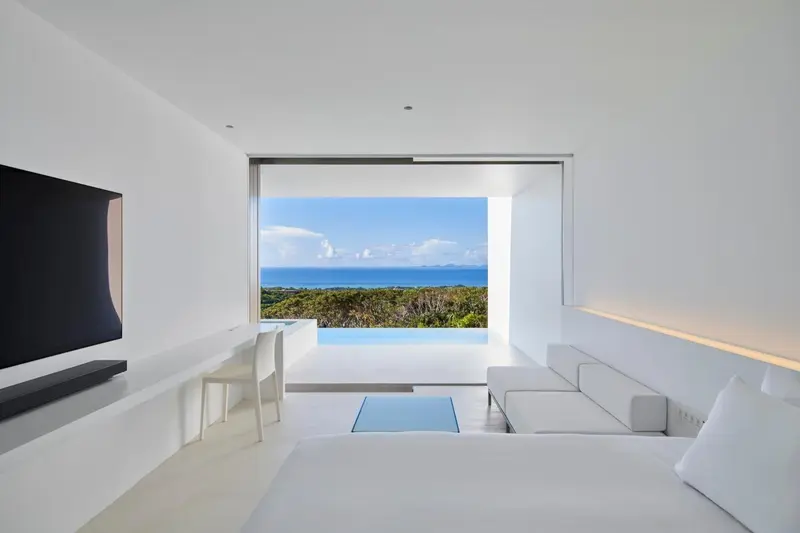 Une chambre lumineuse donne sur une piscine et la mer.