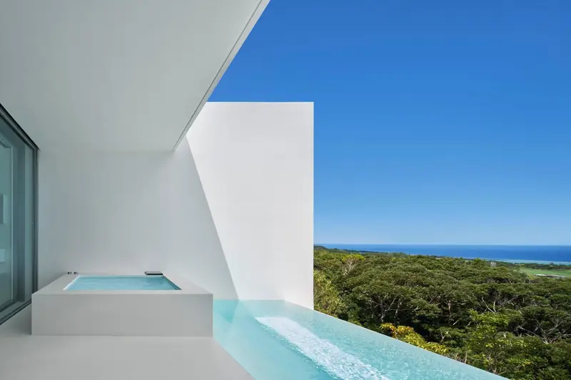 Un jacuzzi extérieur surplombe une végétation luxuriante et la mer.