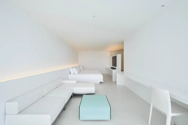 Espace de vie minimaliste avec canapé blanc et table basse lumineuse.