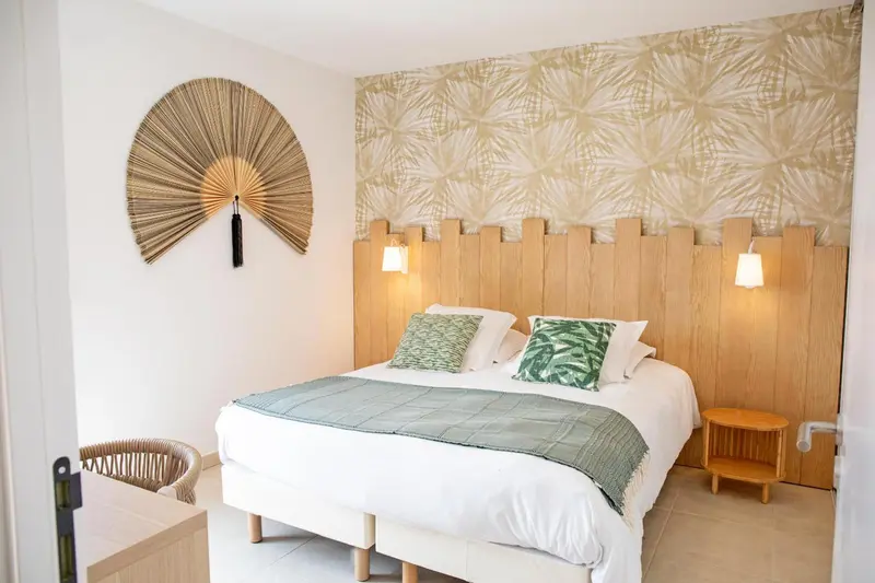 Une chambre lumineuse avec un lit recouvert d'une couverture verte et des oreillers.