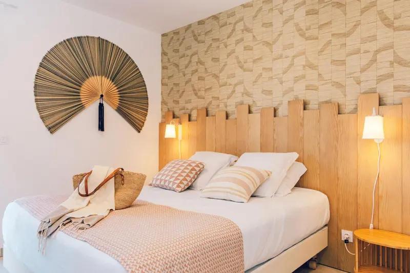 Une chambre lumineuse avec un lit recouvert d'une courtepointe et d'oreillers décoratifs.