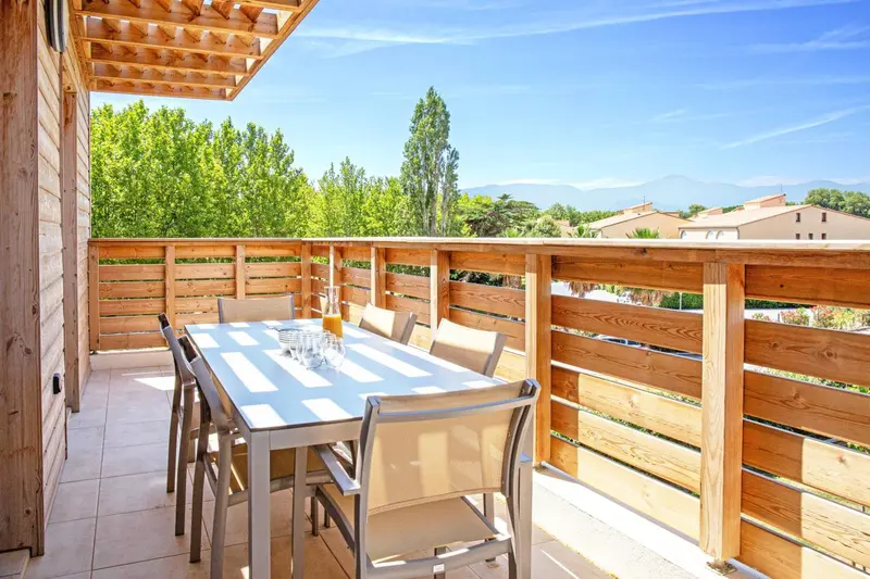 Une table à manger est mise en scène sur une terrasse en bois.