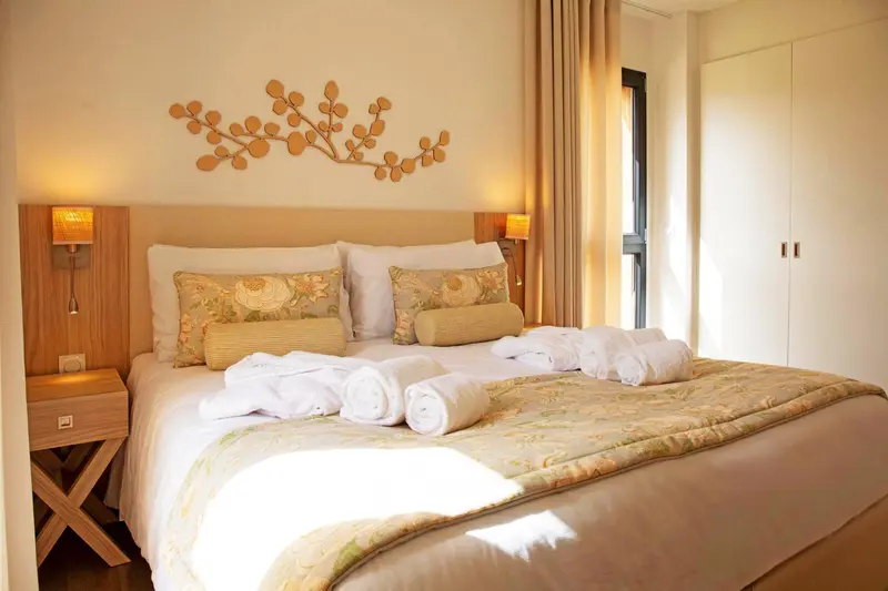 Une chambre lumineuse avec un grand lit recouvert d'une courtepointe et de coussins.