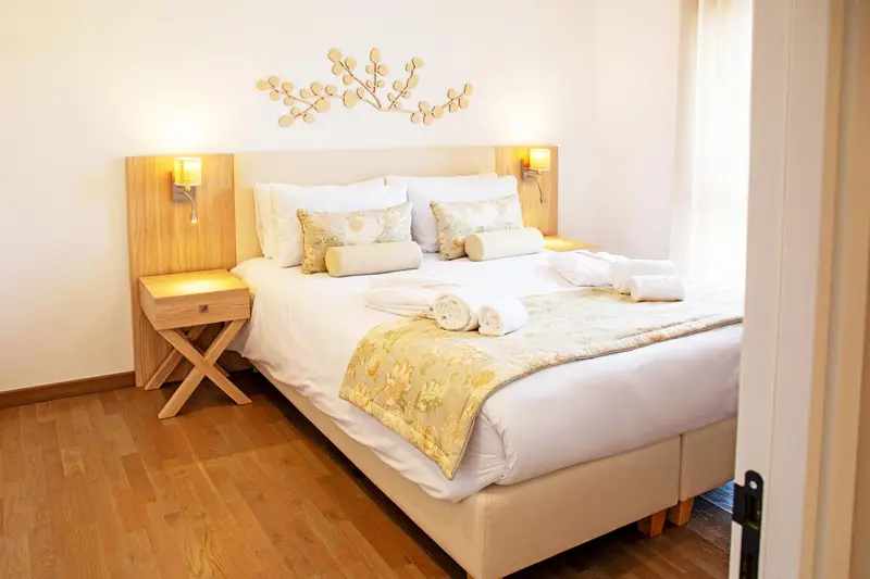 Une chambre lumineuse avec un grand lit recouvert de textiles clairs et décoratifs.