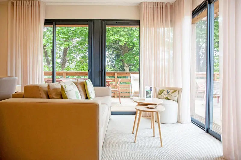 Un salon clair s'ouvre sur une terrasse en bois.