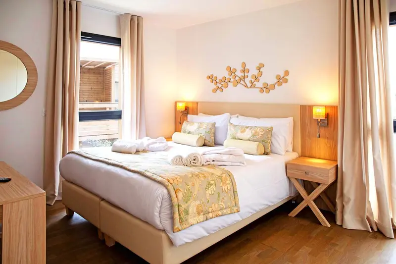 Une chambre lumineuse avec un grand lit décoré de coussins.