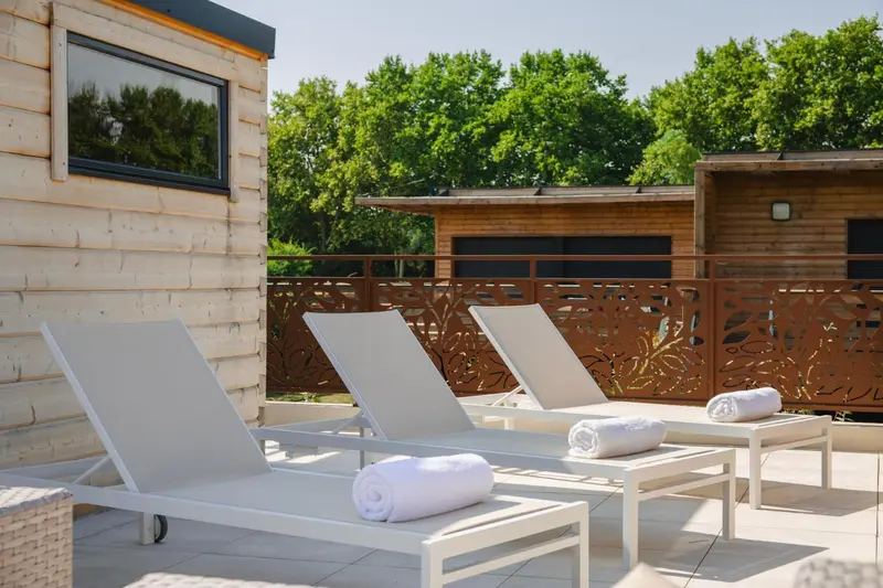 Transats blancs sur une terrasse en bois avec des serviettes enroulées.