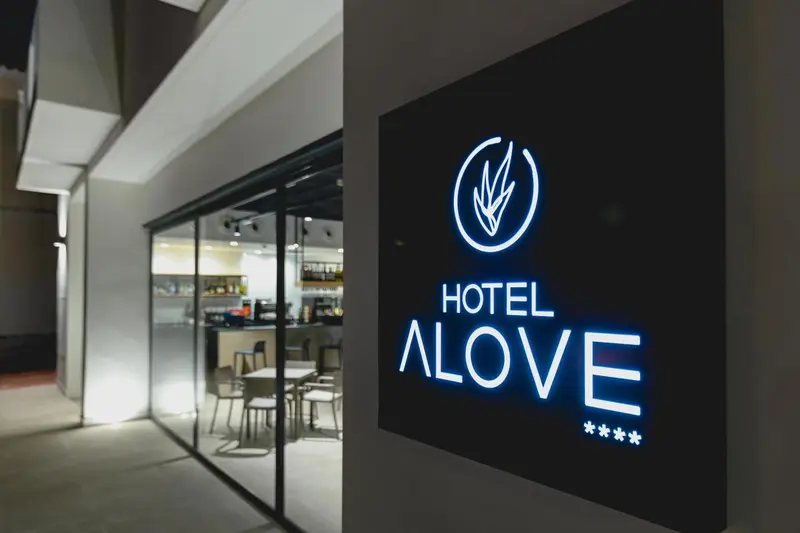 Façade d'hôtel illuminée avec un logo lumineux.