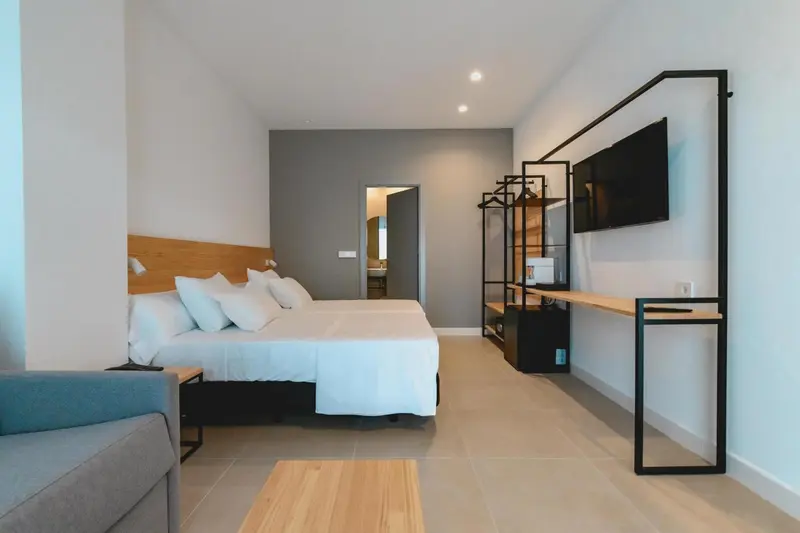Une chambre lumineuse avec un grand lit et un téléviseur mural.