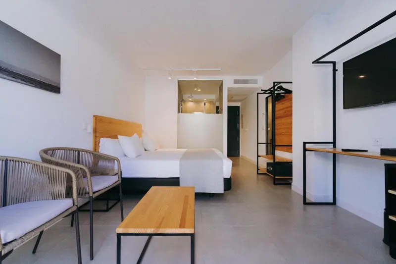 Chambre lumineuse avec un lit double et un coin salon.